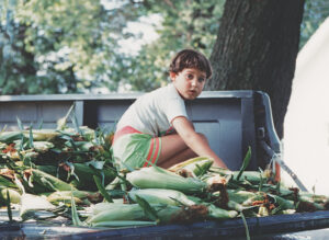 Photo of young Jodi Keen on the back of a pickup truck with husks of corn provided by Donna Keen