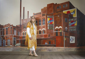 PHOTO OF artist CYNTHIA WATSON with her artwork BY BRODIE CURTSINGER.