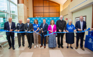 Jim Huebner, Dean Beckman, Mathew Gaug, Lori Persohn, Keith Miller, Nancy Eckerle, Bishop Joseph M. Siegel, Sister Renee Cunningham, and Shawn McCoy participate in the Deaconess Memorial Medical Center ribbon cutting on Aug. 1 in Jasper, Indiana. The longtime health care facility became affiliated with the Deaconess Health System in 2023 and officially unveiled its new name at the ceremony. Photo by Grace Pritchett/Deaconess Health System