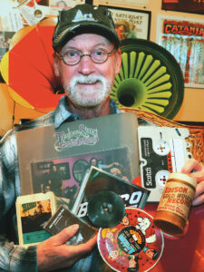 Art Woodward poses with his music collection, which includes CDs, cassettes, vinyl records, and more.