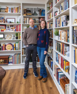 Joshua Claybourn and Melissa Cooney-Mudd stand before shelves of books that make up their home library.