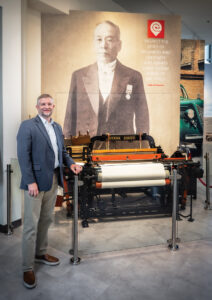 Toyota Indiana President Jason Puckett stands inside its Experience Center near an antique a loom machine.