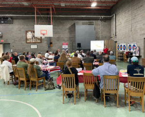 People sit at tables and chairs listening to a speaker