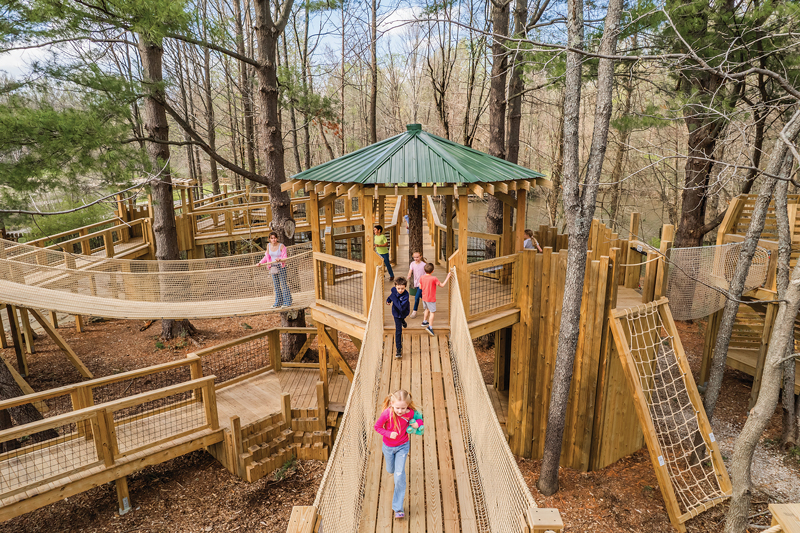 Kids playing in a two-story treehouse in a forest