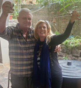 Two people side-hugging and raising glasses for a toast