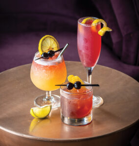three cocktails of different sizes with fruit garnishes