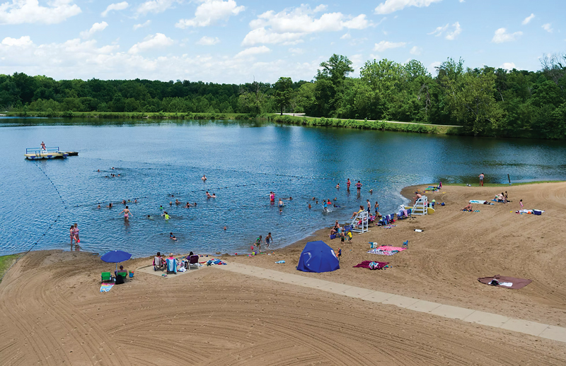 People swimming and lounging on a lakeside beach
