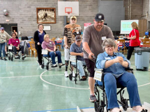 People in wheelchairs are pushed by people walking behind them