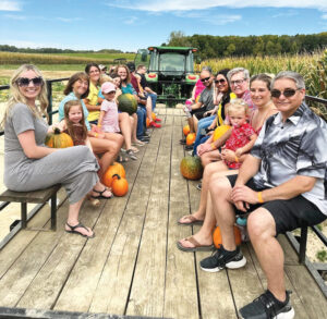 People sitting on a tractor ride through a pumpkin patch