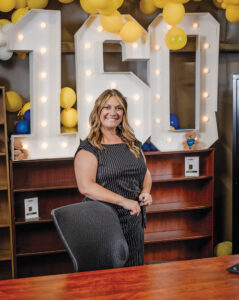 A woman stands in front of enlarged numbers spelling "160"