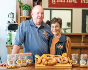 Two people stand with with a display of hard and soft pretzels