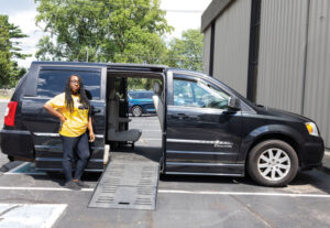 A woman poses next to the open door of a minivan