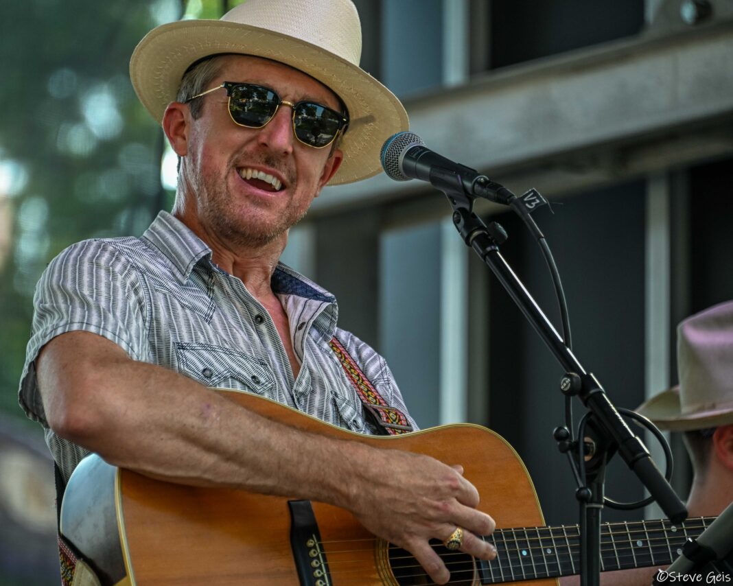 A musician strums a guitar and sings