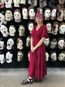 woman standing in front of wall of masks Tian Moore-Denk